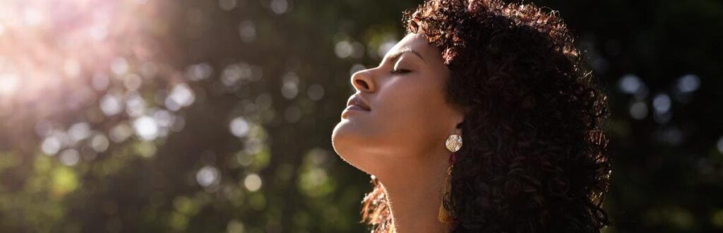 young woman outside with her eyes closed and face turned towards the sun