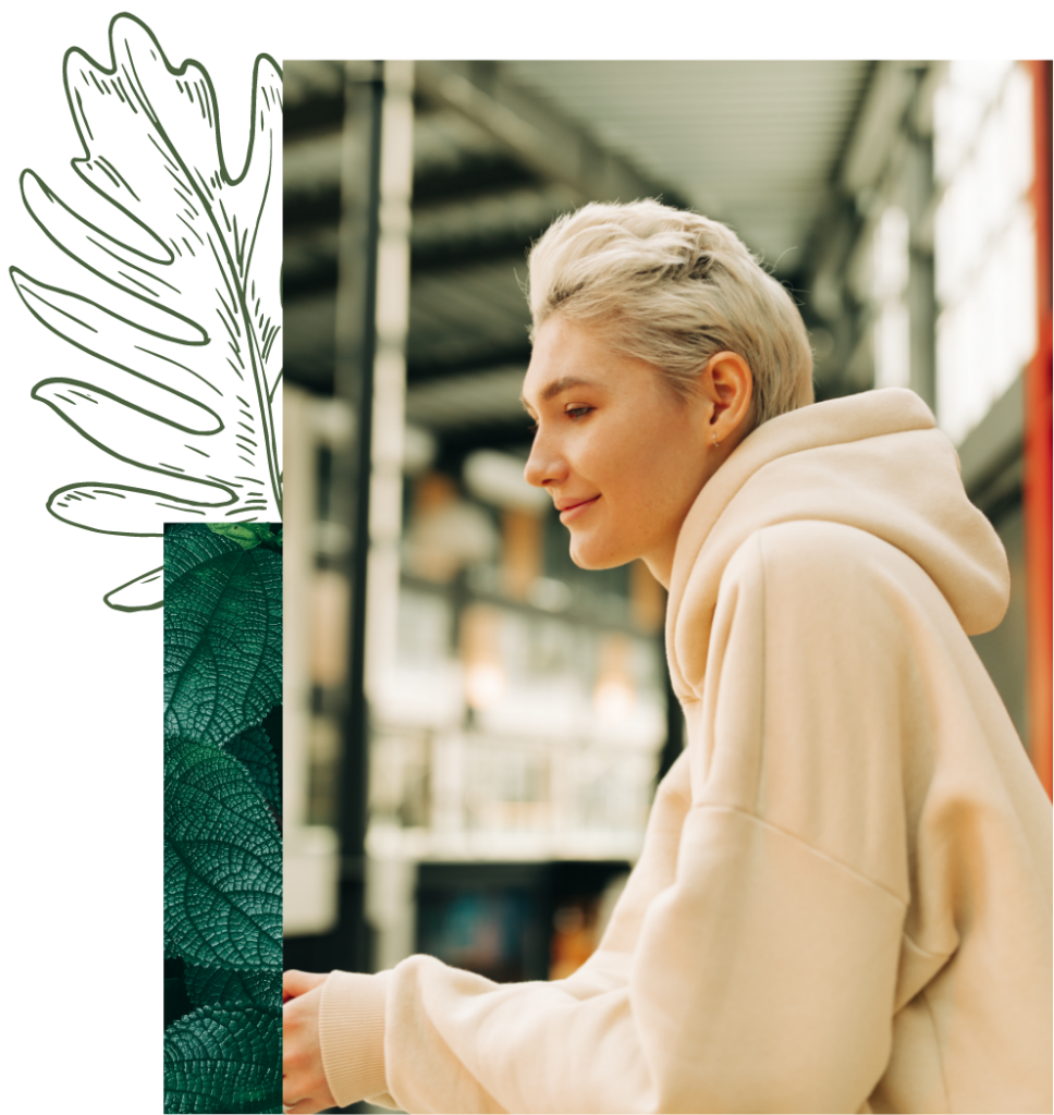 young woman in hoodie with short blond hair standing on a balcony and looking into the distance