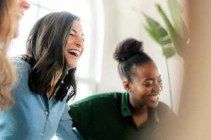 close up of three women with arms around each other laughing joyfully