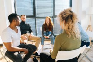 group therapy session of men and women where the therapist is explaining the 5 benefits of an outpatient program